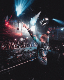 a man playing a dj set in front of a crowd with a shirt that says ' oasis ' on the back