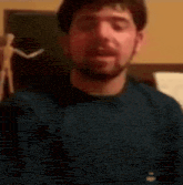 a man with a beard is wearing a blue shirt and making a face .
