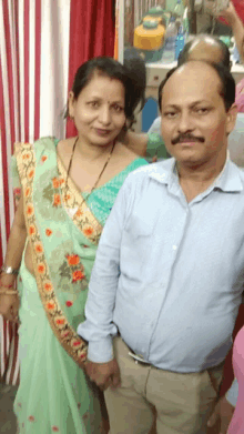 a man and a woman pose for a picture in front of a red and white curtain