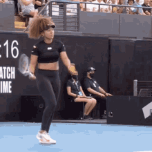 a woman is holding a tennis racquet on a tennis court in front of a sign that says match time