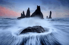 a group of rocks in the ocean with waves crashing on them