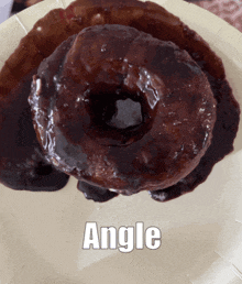 a chocolate glazed donut on a paper plate with the word angle above it