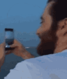 a man with a beard is drinking a glass of water