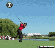 a man in a red shirt is kneeling down on a golf course with a cbs logo in the background