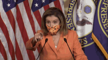 a woman wearing a face mask stands in front of a podium with a flag that says congress in the background