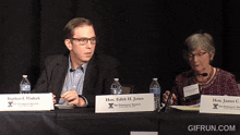 a man and a woman sit at a table with a sign that says hon. edith h. jones on it