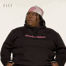 a woman wearing a black balenciaga hoodie and a pink head scarf