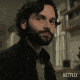 a close up of a man with a beard and a netflix logo behind him