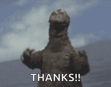 a statue of a dinosaur is waving and saying `` thanks ! ''