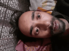 a man with a beard is laying on a bed with his eyes closed