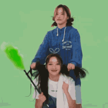 two girls are playing with their hair and one of them is holding a dusting brush .