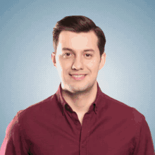 a man in a maroon shirt is smiling for the camera