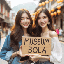 two women holding up a sign that says museum bola