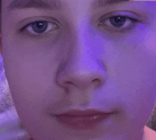 a close up of a person 's face with purple light behind them