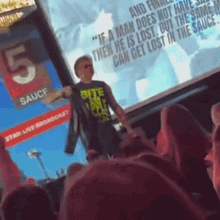 a man stands in front of a screen that says " if a man does not have sauce then he is lost "