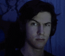 a young man wearing headphones is making a funny face in a dark room .