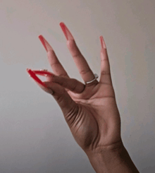 a woman 's hand with red nails and a diamond ring