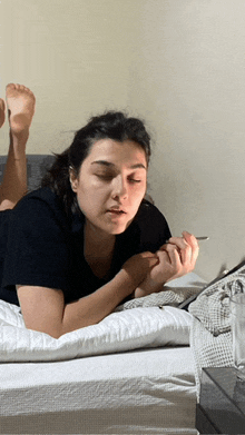 a woman is laying on her stomach on a bed holding a cigarette