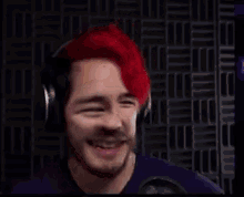 a man with red hair and headphones is smiling .