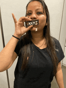 a woman in a black shirt holds a laxmi bar in front of her face