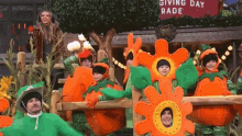 a group of people dressed as pumpkins are dancing in front of a sign that says " giving day rade "