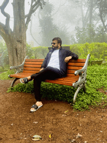 a man sits on a wooden bench with his legs crossed and wearing sandals