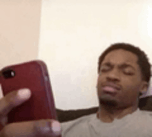 a man is sitting on a couch looking at a cell phone .