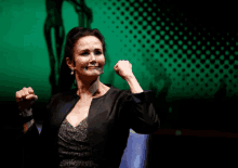 a woman with her fist in the air is wearing a black jacket