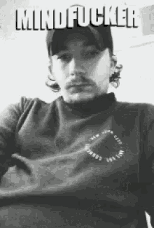 a man wearing a hat and a sweater with the words mindfucker on the top
