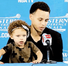 a man and a child are sitting in front of a microphone in front of a sign that says western conference finals