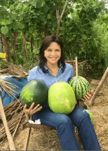 a woman is sitting in a chair holding two watermelons .