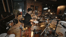 a man is playing drums in a room with a lot of drums .