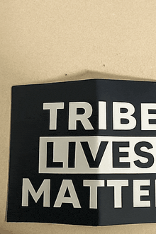 a black sign that says tribe lives matter on it