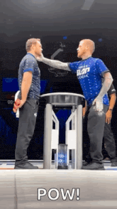 two men are standing next to each other on a stage and one of them is slapping the other 's face .