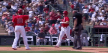 a baseball player wearing a red jersey with the number 10 on it is walking towards another player on the field .