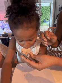 a little girl with curly hair is eating a piece of food