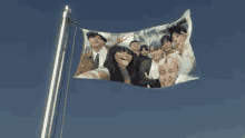 a flag with a picture of a group of people flying in the sky .