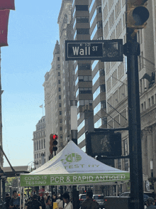 a sign for wall street is above a tent that says pcr and rapid antigen