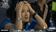 a woman holds her head while watching a sports game on espn