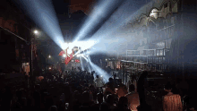 a crowd of people are gathered in a dark room with a light shining through the ceiling