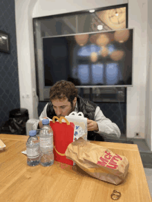 a man sits at a table with a bag of mcdonald 's happy meal