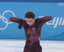 a female figure skater is standing in front of an olympic sign