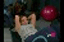 a blurry picture of a person sitting on a couch with a red ball in the background .