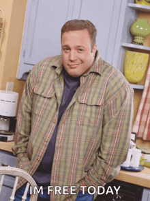 a man in a plaid shirt stands in a kitchen with his hands in his pockets and the words im free today below him