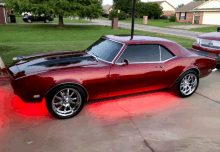 a red car is parked in a driveway with red lights on the tires