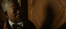 a man wearing glasses and a bow tie says " oh i stand corrected "