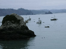 a few boats are in the water near a rocky shoreline