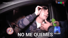 a man sitting in a car with the words " no me quemes " on the screen