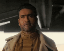 a man with a beard is wearing a fur jacket and a brown turtleneck .