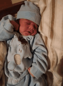 a baby is wearing a blue outfit with a cloud on it and a hat